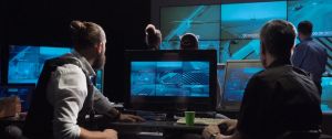 Des hommes dans une piece sombre qui regardent des écrans