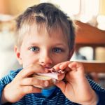 un jeune garçon mange un sandwich au jambon
