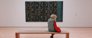 une jeune femme au musée assise devant un tableau