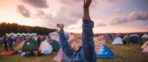 Jeune femme danse et lève les bras pendant un festival de musique.