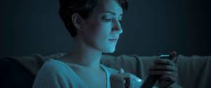 Une femme qui regarde son écran de téléphone dans le noir