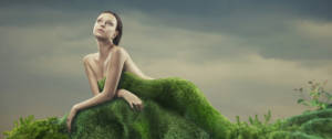 Une femme nue derrière une butte d'herbe