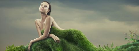 Une femme nue derrière une butte d'herbe