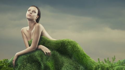 Une femme nue derrière une butte d'herbe