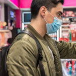 un homme portant un masque en train de faire ses courses au supermarché