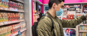 un homme portant un masque en train de faire ses courses au supermarché