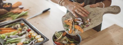 Une femme en train de jeter des épluchures de légumes