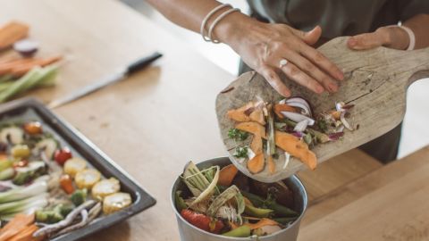 Une femme en train de jeter des épluchures de légumes