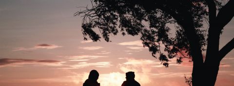 deux jeunes qui parlent assis face au coucher du soleil