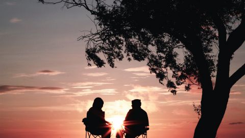 deux jeunes qui parlent assis face au coucher du soleil