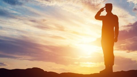Un officier faisant un salut sur un fond de soleil couchant
