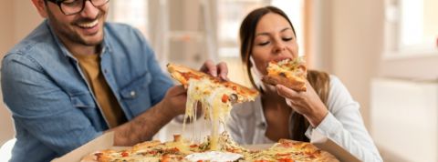 Un homme et une femme en train de manger une pizza