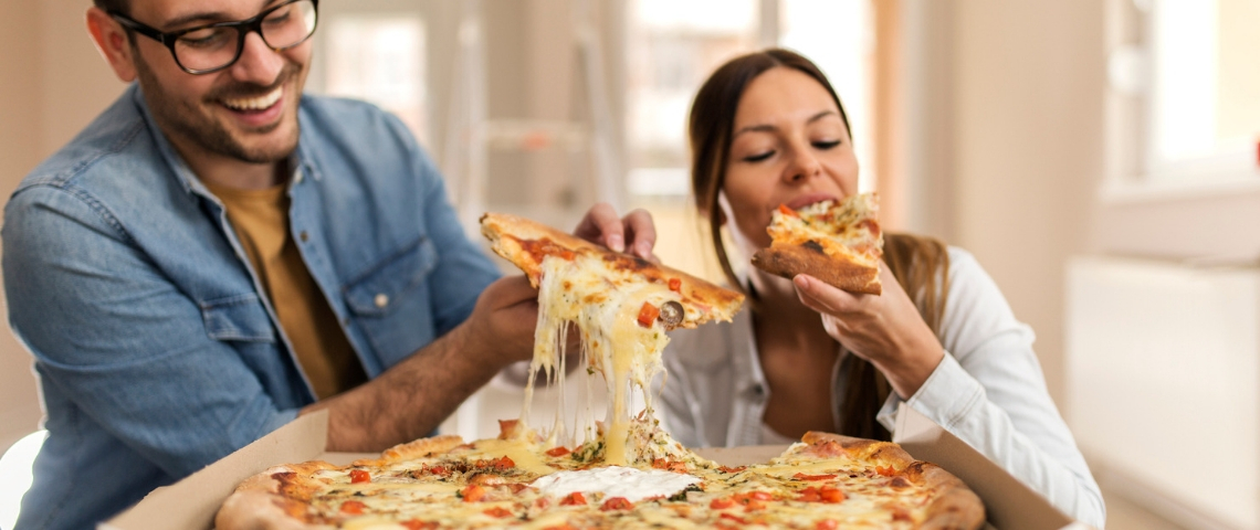 Un homme et une femme en train de manger une pizza