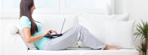 Une femme travaillant sur son canapé en jogging et pieds nus