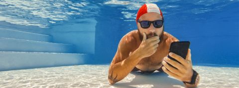 Homme au fond d'une piscine avec son portable