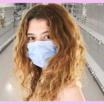 Une fille blonde avec un masque blanc dans un aéroport vide