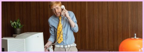 Un homme au téléphone debout derrière son bureau