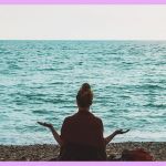 Une femme qui médite sur la plage face à la mer