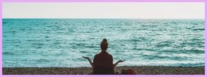 Une femme qui médite sur la plage face à la mer