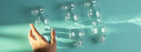 Une main qui s'approche de trois bouteilles en plastique