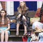 Quatre filles assises sur un escalier devant un immeuble de briques rouges