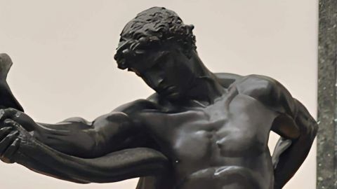 une statue d'homme tenant un serpent à bout de bras
