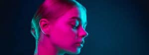 Jeune femme au visage éclairé d'une lumière rose fluo