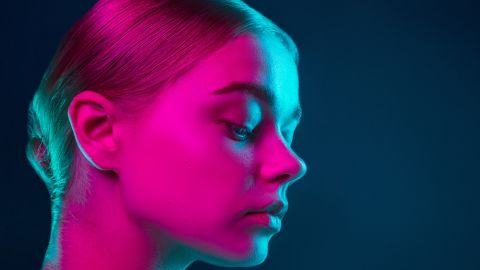 Jeune femme au visage éclairé d'une lumière rose fluo