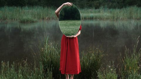 Femme se cachant derrière un miroir