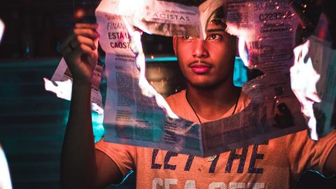 Un jeune homme tient un journal qui brûle