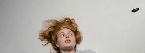 Un jeune femme rousse effrayée par un cafard qui se dirige vers elle
