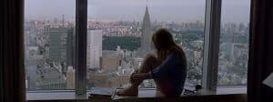Une silhouette de femme qui regarde la ville d'une fenêtre
