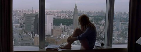 Une silhouette de femme qui regarde la ville d'une fenêtre