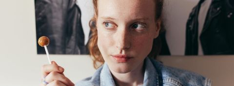 Une jeune femme rousse, regard au ciel avec une sucette