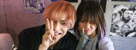 Un jeune homme cheveux orange et une jeune fille brune, tous deux asiatiques font des grimaces