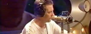 un homme à moustache devant un micro de radio