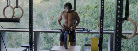Un homme métissé fait de la musculation avec en fond la jungle de Bali