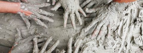 Plusieurs paires de mains pleines d'argile en contact d'argile