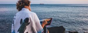 Un jeune homme de dos peint la mer