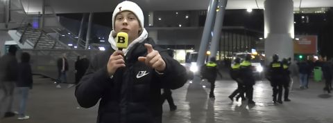 une jeune garçon au bonnet blanc devant un stade