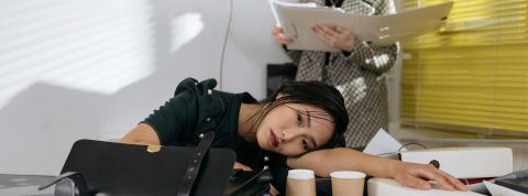 femme allongeant sa tête sur une table de bureau