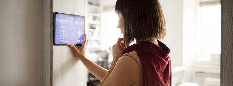 femme régulant la température de son appartement avec un appareil connecté