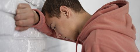 Un jeune garçon tête contre le mur, super déprimé