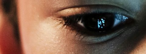 Le regard d'une jeun garçon dans le vide avec le reflet d'un écran dans son iris