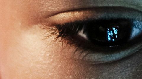 Le regard d'une jeun garçon dans le vide avec le reflet d'un écran dans son iris