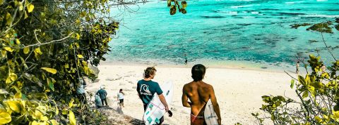 Deux surfers et plusierus personnes sur une plage balinaise