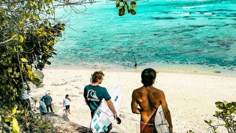 Deux surfers et plusierus personnes sur une plage balinaise