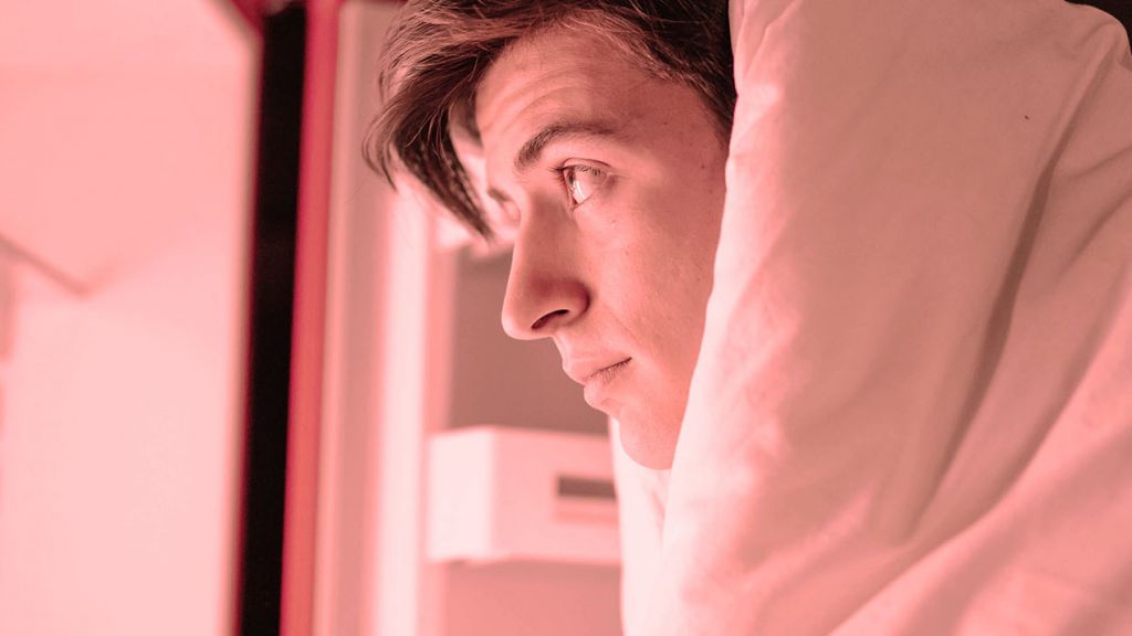 Un homme dans sa couetet regarde le contenu du frigo