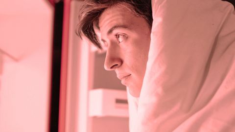 Un homme dans sa couetet regarde le contenu du frigo