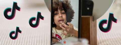 Une jeune influenceuse devant son téléphone avec des logos TikTok